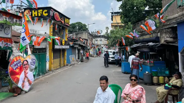 People sitting on the street, with a small eatery in the background. The shops are all closed.