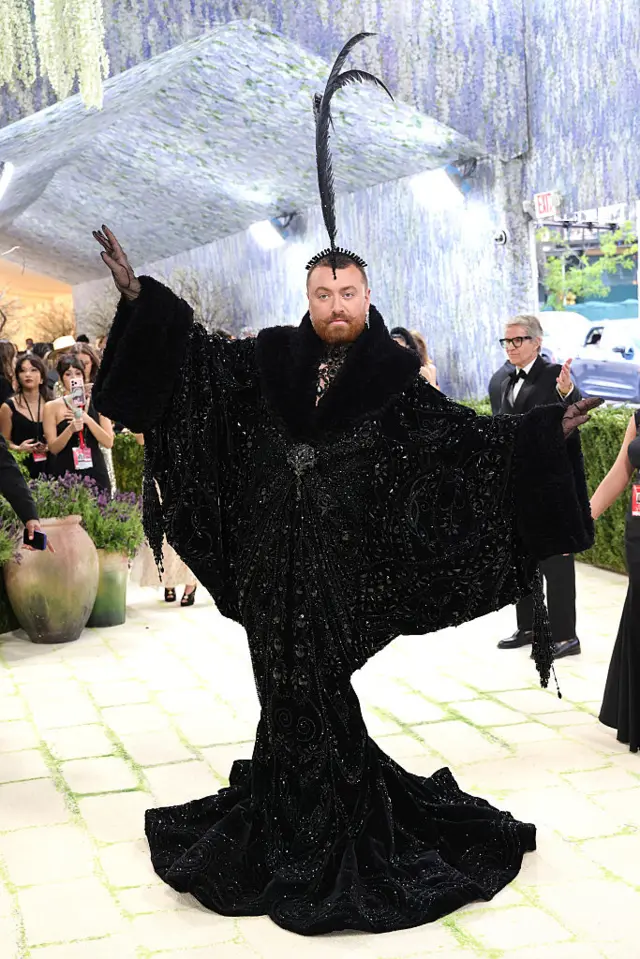Singer Sam Smith arrives in a flowing black gown with striking black feather fascinator