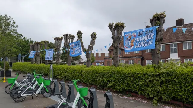"We Are Premier League" Coventry city posters hung on trees on a street