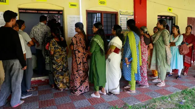 People stand in queues to cast their votes at a polling station during the Kerala state assembly election in Kochi, India, on April 9, 2026