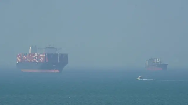 Two commercial ships are shown anchored in the Strait of Hormuz.