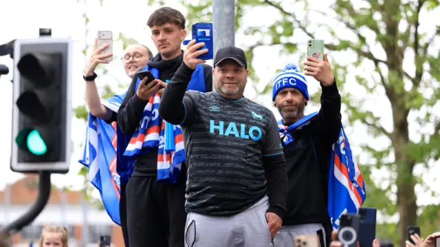 A group of four people all filming the parade bus