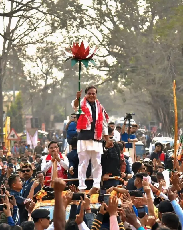 Assam CM Himanta Biswa Sarma standing on top of a vehicle with a placard shaped like a Lotus - the BJP's election symbol - celebrating the party's lead in early election trends on 4 May
