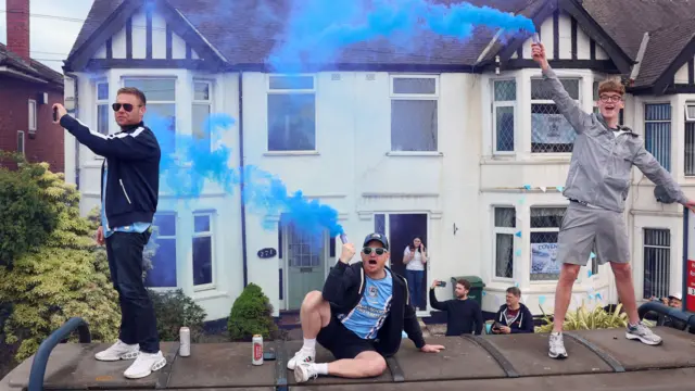 Coventry City fans on top of a bus stop during the parade as they celebrate promotion to Premier League