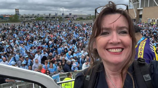 A woman takes a selfie with all the fans behind her