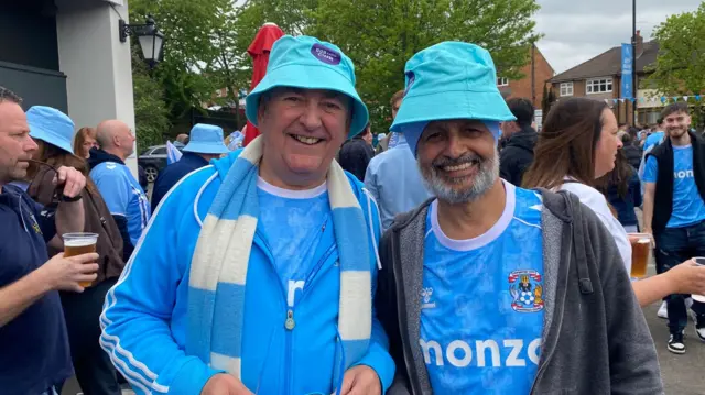 Two men wearing Coventry City shirts and sky blue bucket hats