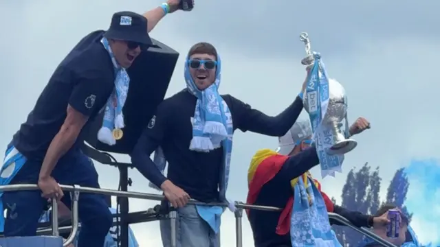 Players lifting the trophy on the bus