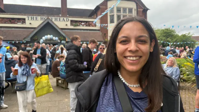A woman stands in front of a pub