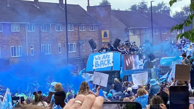 Phones take photos of the bus as it goes past