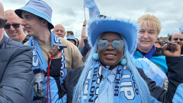 Woman wearing Sky Blues kit, scarf and hat