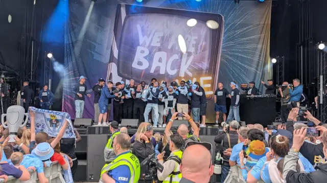 Players celebrate on stage while fans cheer