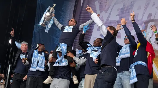 The trophy in midair as players celebrate