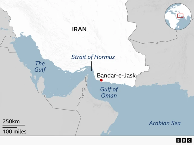 Map showing Iran’s southern coast and the Strait of Hormuz between the Gulf and the Gulf of Oman. Iran is labelled, with Bandar‑e‑Jask marked on the coast near the eastern entrance to the strait. The Arabian Sea lies to the south east, and an inset globe highlights the location in the wider region.