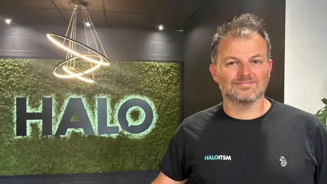 Paul Hamilton standing in front of a Halo logo.