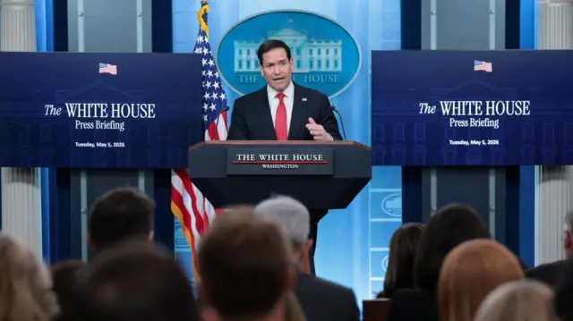 Marco Rubio speaking behind podium, screens behind him say White House Press Briefing.