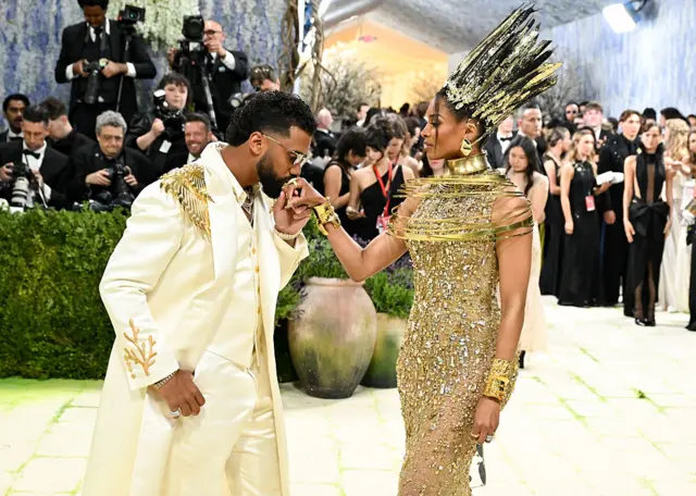 Musician Ciara, wearing all gold, posing with her husband, American footballer Russell Wilson