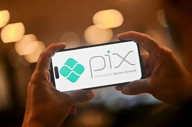 This photo illustration shows a man holding a smartphone displaying the logo of Pix, Brazil's free instant payment system.