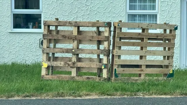Wooden structures are standing up on grass.