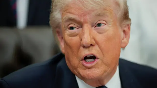 A file photo of President Trump sitting at his desk