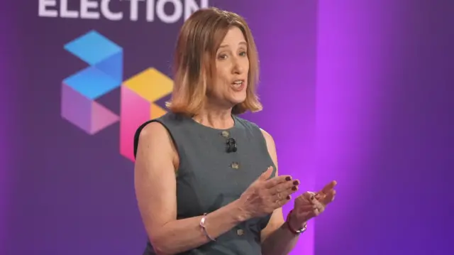 Jane Dodds is standing in front of a purple-lit wall which has "BBC election" written on it