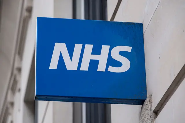 A blue NHS sign on the side of a building