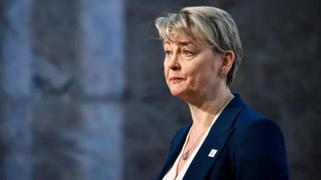 Yvette Cooper headshot as she looks off to the side of the camera wearing a blue suit and white top. The background is blurred