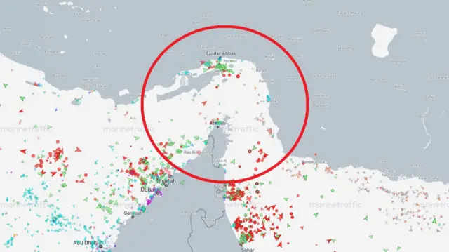 A red circle is shown on a diagram of the Strait of Hormuz, positioned on the strait. Land is shown in dark grey and water white, with red, green, blue and purple colours being used to indicate