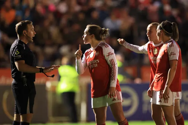 Arsenal players argue with the referee
