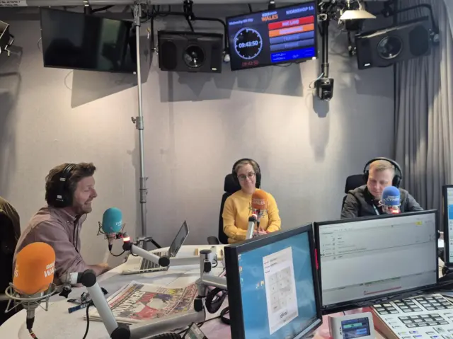 James Williams, Felicity Evans and Daniel Davies sit behind microphones in the BBC Walescast studio