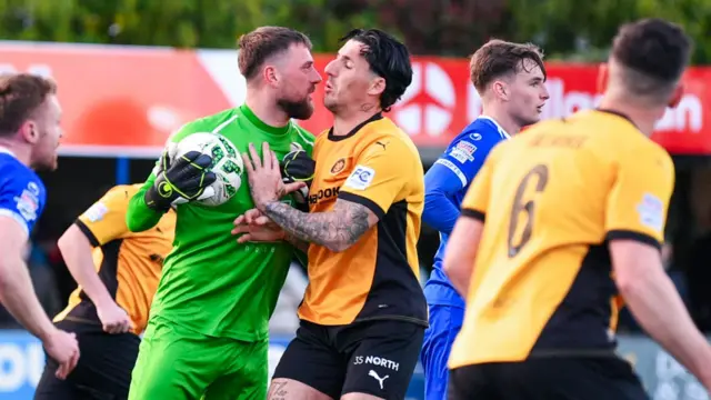 Dungannon Swifts goalkeeper Declan Dunne squares up to Danny Gibson of Carrick Rangers