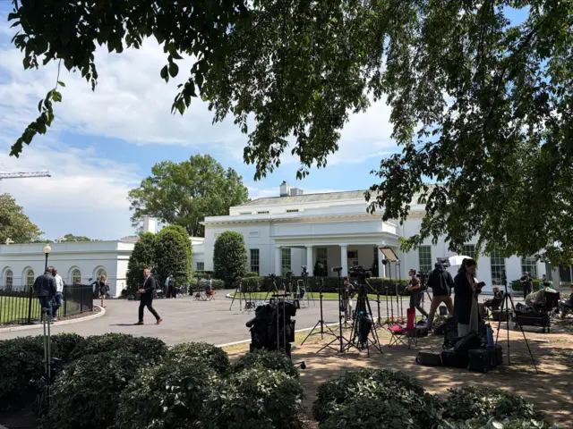The driveway of the West Wing of the White House with camera crews set up for live shots