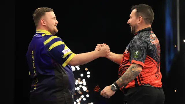 Luke Littler shakes hands with Jonny Clayton after beating him on night fourteen of the BetMGM Premier League 2026 at First Direct Bank, Leeds