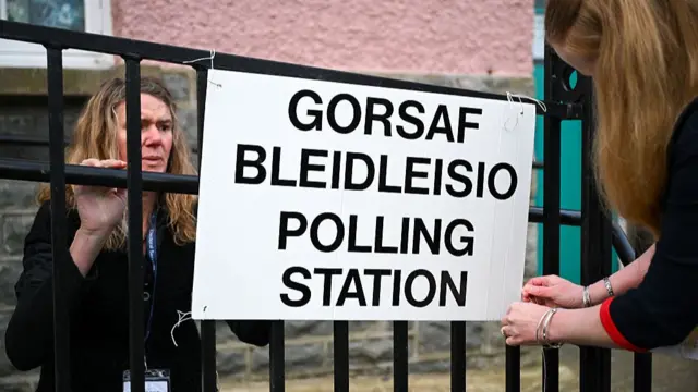 Staff setting up a sign at a polling station in St Davids, Wales
