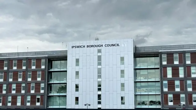 A large five story building made of bricks with white paneling in the middle which has Ipswich Borough Council written across the top in black lettering
