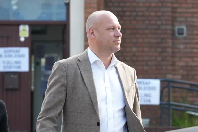 Dan Thomas wearing a light brown jacket and white shirt