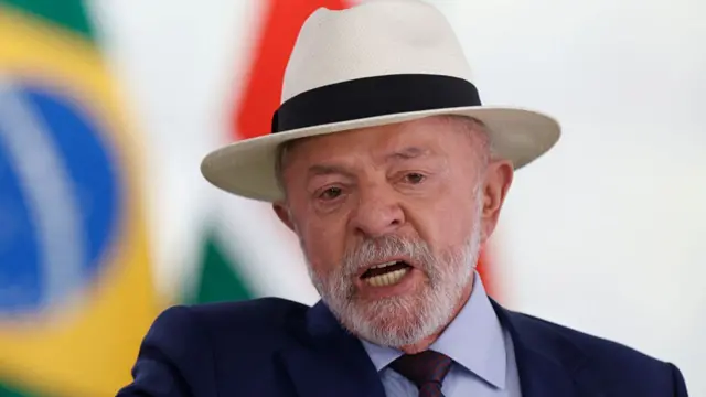 Lula speaks at an event. He wears a white hat and a dark suit