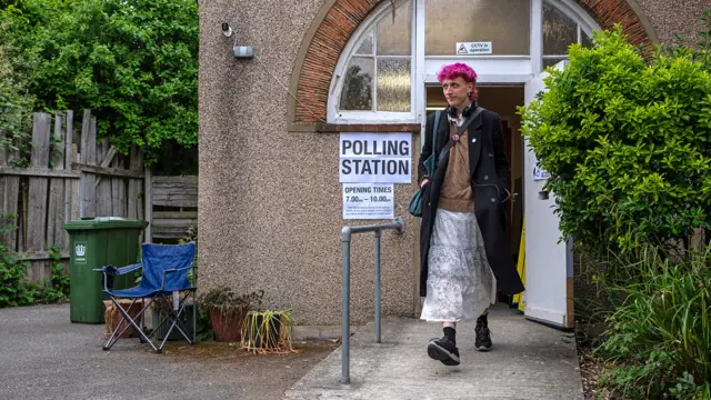 A person walks out of a voting station next to a sign reading 'polling station' in Lewisham on Thursday