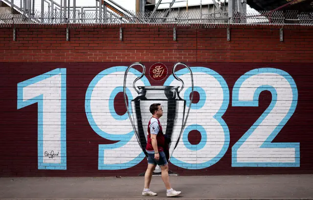 VIlla fan walks past a 1982 European Cup commemorative mural outside Villa Park