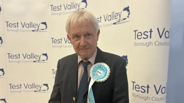 Harry Sheffield a man with white hair, wearing a suit and wearing a light blue rosette on his chest.