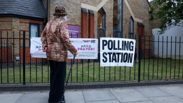 A person stands outside a church being used as a polling station before the polls open and voting begins in local elections, in Fulham, London,