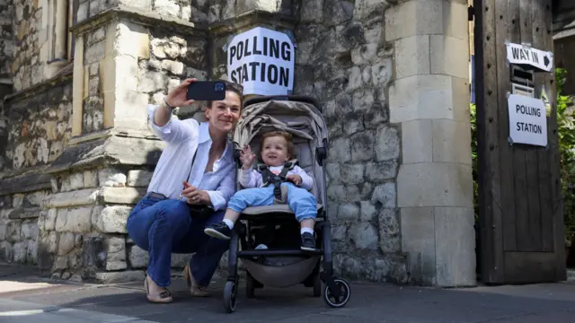 A woman takes a selfie with a child outside a polling station at the Church of St Barnabas in Pimlico