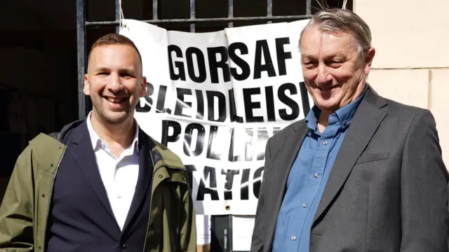 Zach Polanski and Anthony Slaughter stand in front of a polling station sign