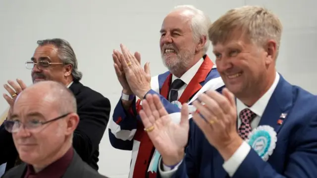 Reform UK activists, including newly elected councillor for Clacton North Peter Harris (right), celebrate at Essex County Council count at Clacton Leisure Centre