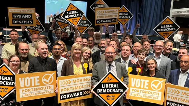 A group of people holding up Lib Dem signs