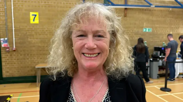 Lulu Bowerman a woman stood in a hall smiling at the camera.