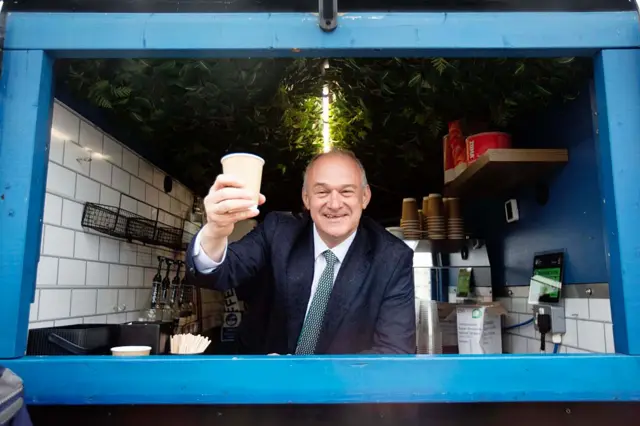 Ed Davey holds up a cup of coffee