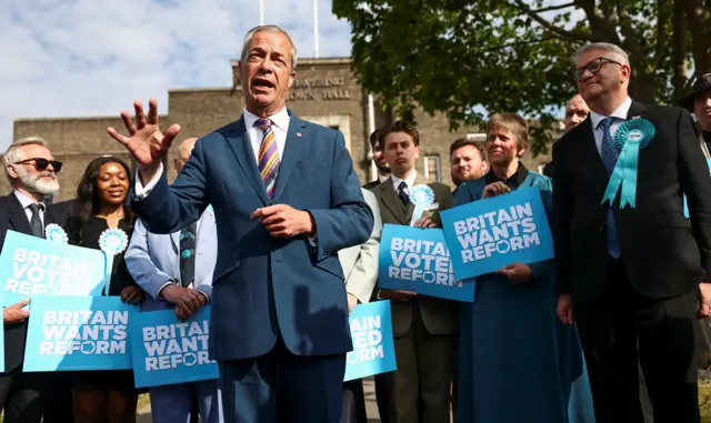 Farage gestures as he speaks in front of a flock of Reform campaigners holding signs reading 'Britain wants Reform' in Havering on Friday.