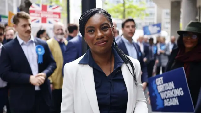 Badenoch smiles as she walks with Conservative supporters behind her