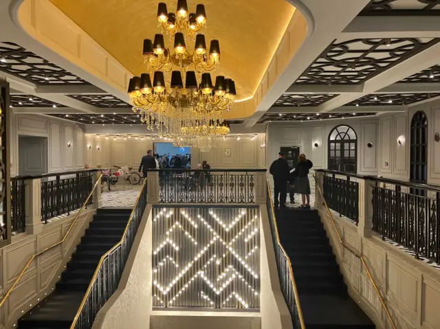 An intricate chandelier hangs above a grand staircase.