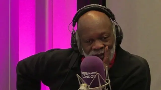 Eddie Nestor  sitting behind a BBC Radio London microphone